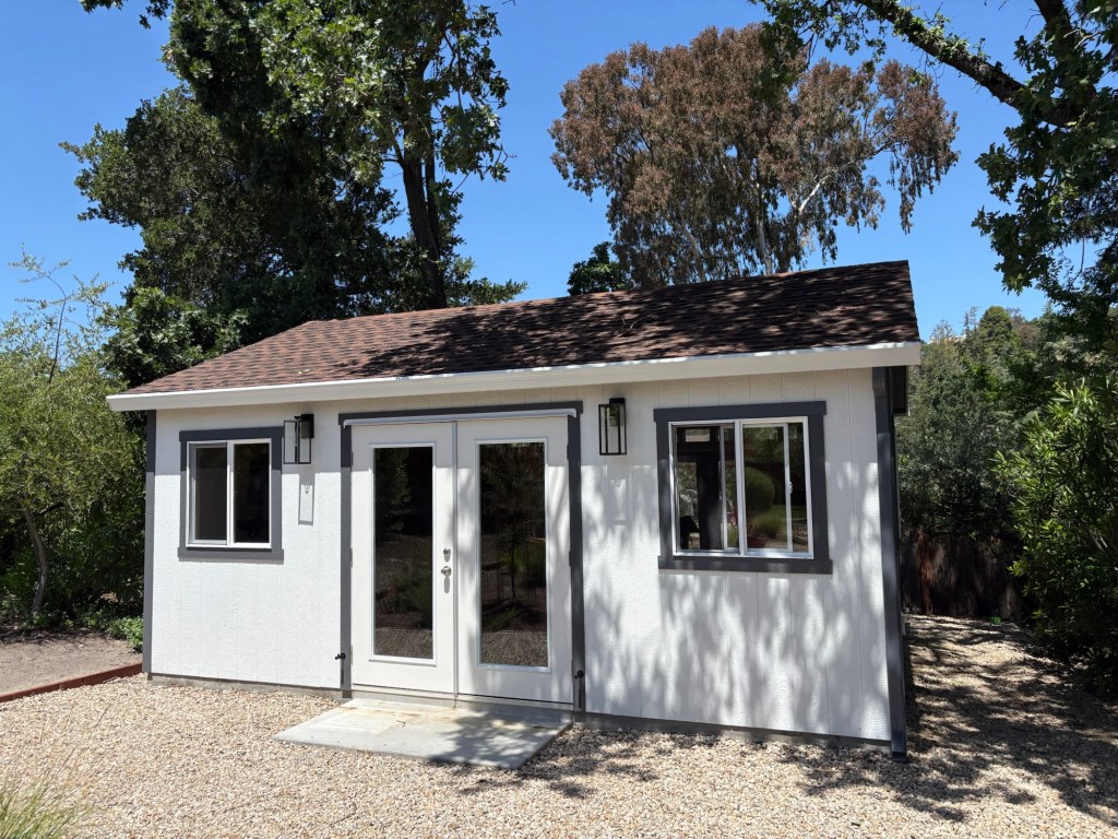 Exterior view of the finished white gym shed with glass doors and gutters