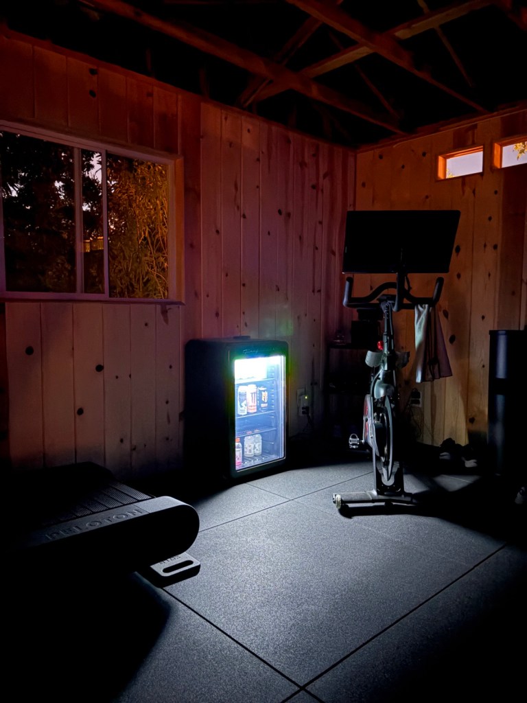 Gym at night with Peloton bike and glowing cooler