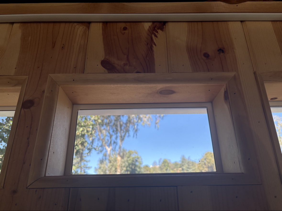 Close-up of the deep wood window jamb and trim meeting the pine plank wall