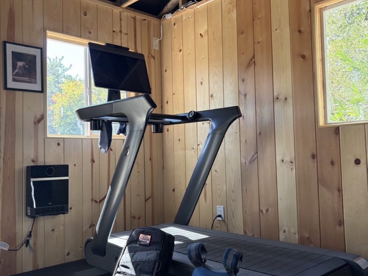 GORUCK Rucker backpack and weighted vest labeled next to the Peloton Tread+ in the shed gym